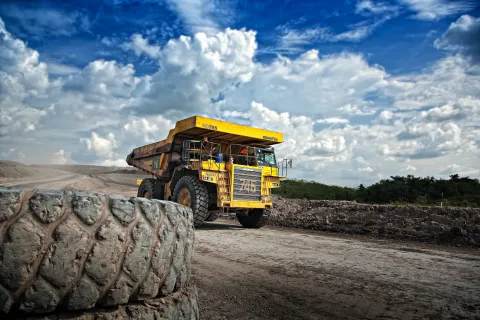 a large yellow truck drives down a dirt road