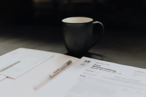 a cup of coffee and a pen on a table