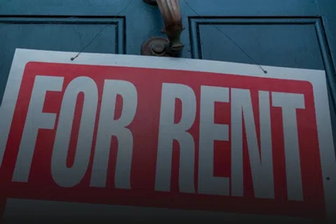 Red and white For Rent sign hanging on a blue door with a metallic door handle above it.