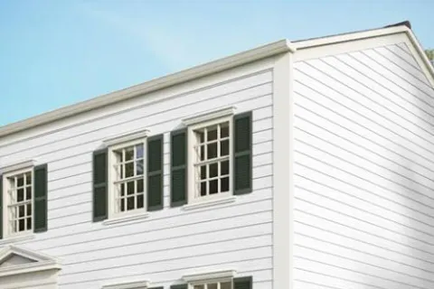 White house exterior with green window shutters under clear blue sky daylight