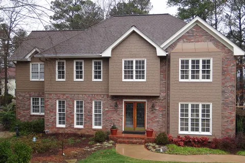 Charming suburban home with brick facade, large windows, and manicured landscaping.