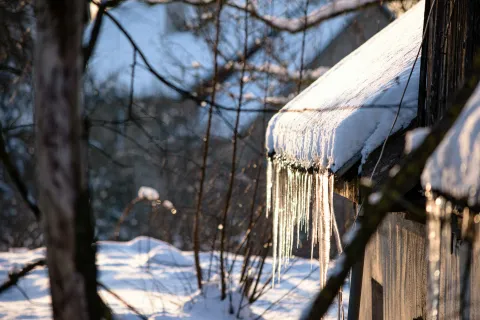 Winter ice damage on residential roof with icicles hanging from gutters