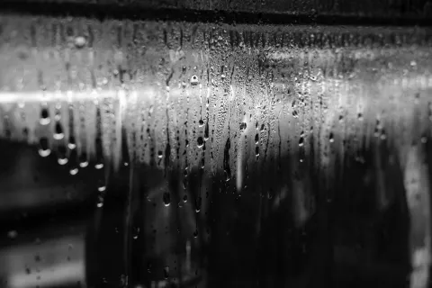 Close-up of condensation on a glass surface, creating a blurred, textured effect with droplets.