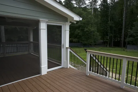 a deck with a white building and trees in the background