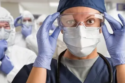 Healthcare professionals in PPE preparing for a medical procedure in a hospital setting.
