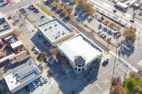 Aerial view of a city block featuring commercial buildings and parked cars.