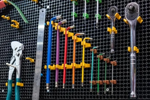 Colorful tools organized on a tool wall, showcasing various pliers and wrenches neatly arranged.