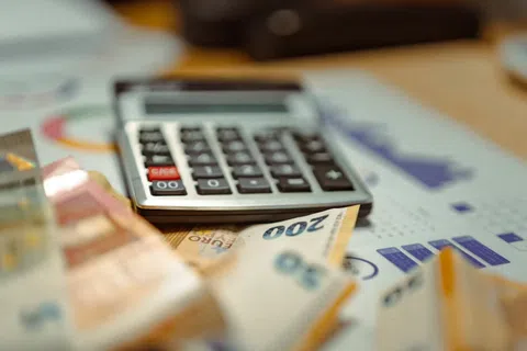 Calculator on financial charts with scattered euro banknotes indicating budgeting and finance management.