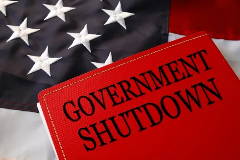 Red folder labeled Government Shutdown on an American flag background symbolizing US government closure.