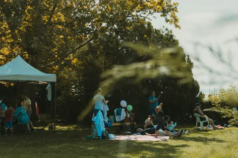 a group of people sitting on the ground with a tree and a fire