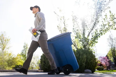 Pest control technician bringing in customers trashcan to keep the property clean to avoid pest activity.