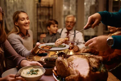 Family enjoying a festive meal with roasted turkey, serving green beans and mashed potatoes together at the dinner table.