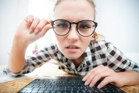 a person with glasses looking at a laptop