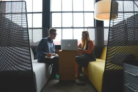 a man and a woman sitting at a table with a laptop
