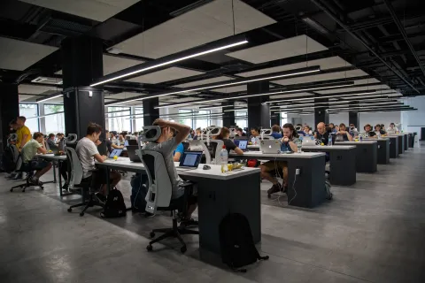a group of people sitting at desks in a large room