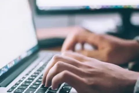 close-up of hands typing on a laptop