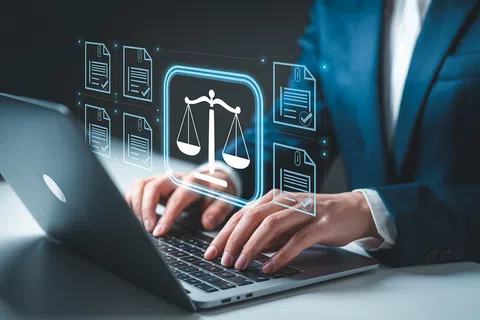 Person in suit typing on laptop with floating icons of legal scales and documents representing law and digital compliance.