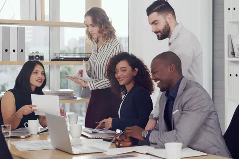 Diverse business team collaborating with documents and laptop during a positive office meeting