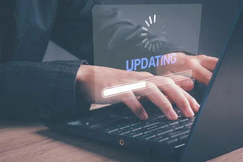 Person typing on laptop with digital update progress bar and loading icon overlayed on screen.