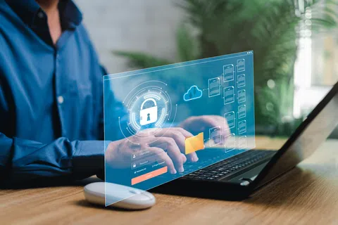 Person typing on laptop with digital security icons including padlock, cloud, and folder interface overlay.
