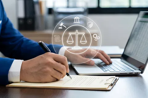Man in suit writing on legal document with laptop and law icons overlay, symbolizing legal work and compliance.