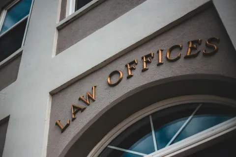 Curved building facade with golden letters spelling LAW OFFICES above arched window reflecting sky.