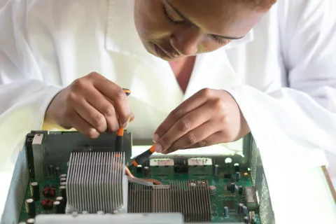 Technician carefully repairing or assembling electronic circuit board inside a computer with tools