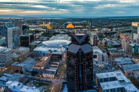 Aerial view of downtown Sacramento at sunset with skyscrapers and cityscape under a cloudy sky.