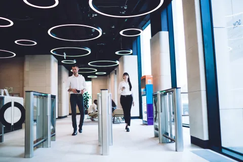 a man and woman standing in a room with blue walls and a large logo