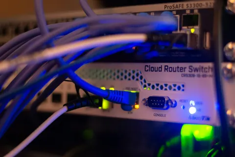 Close-up of a cloud router switch with multiple blue Ethernet cables plugged in and LED indicator lights glowing.