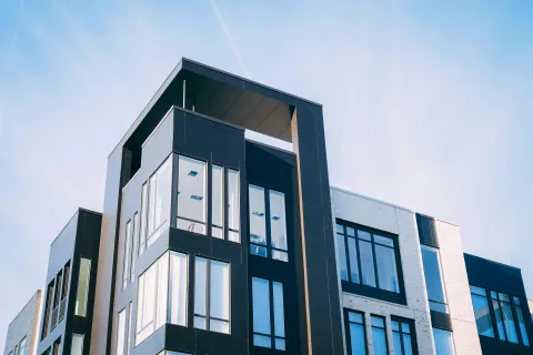 Modern apartment building with large windows and black and white facade under clear sky.