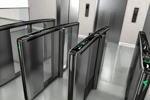 Modern black and glass security gates with digital access panels in an office building entrance.