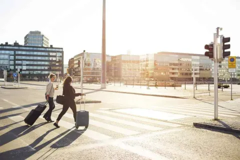 people with luggage walking across a crosswalk