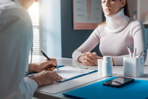 a patient with a neck brace consulting with a doctor