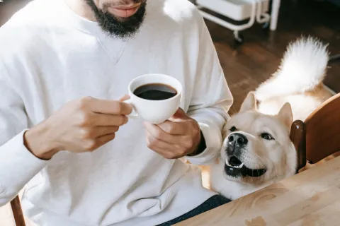 a man holding a cup of coffee and a dog