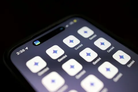 Smartphone screen showing multiple Gemini app icons with star-like logo on a dark background.