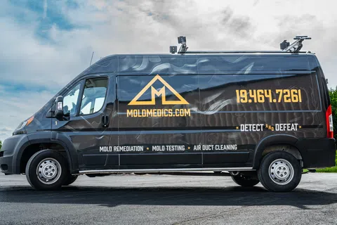 Black Mold Medics van with company logo, phone number, and services including mold remediation and air duct cleaning.