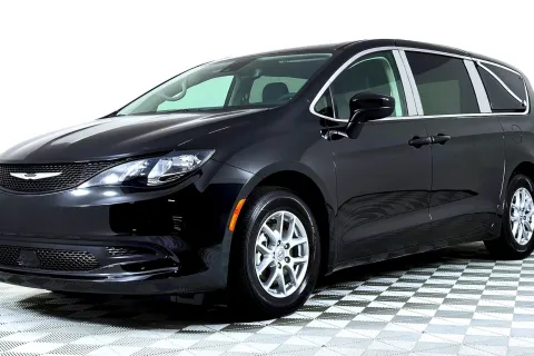 Black Chrysler minivan parked on checkered floor against white background, showing front and side view.