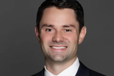 Smiling man wearing navy suit and yellow tie on dark gray background professional portrait