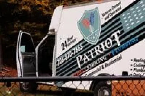 Security patrol vehicle parked with open door behind chain-link fence in an outdoor setting