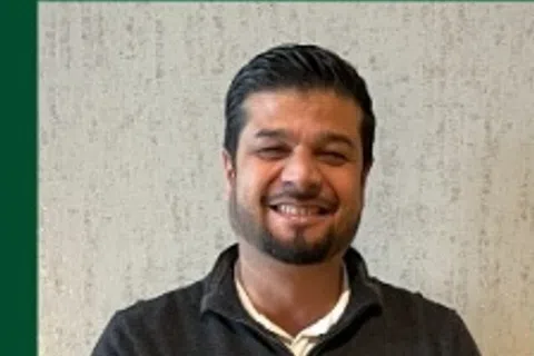 Smiling PestMaster franchisee in a dark sweater, standing against a textured background, with name displayed below.