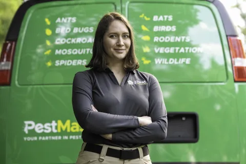 A woman standing in front of a green PestMaster truck