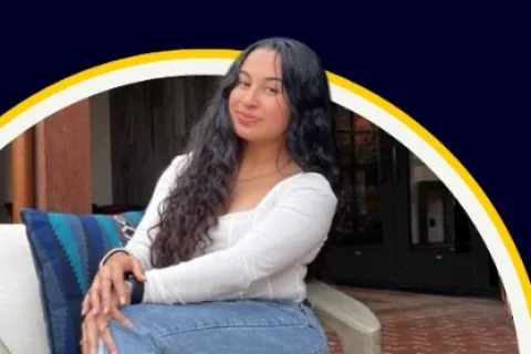 Young woman with long curly hair sitting on a chair outdoors smiling at the camera