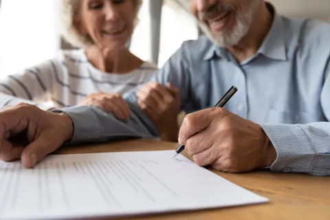 a man and a woman sitting at a table and looking at a paper