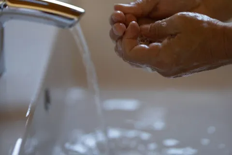 a hand pouring liquid into a faucet