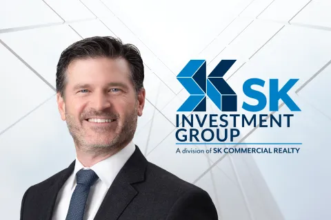 Professional businessman in suit smiling with SK Investment Group logo and tagline in background