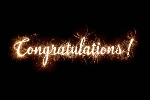 Sparkler light spells out Congratulations! on a black background with bright glowing sparks.