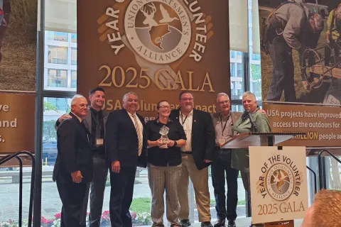Group of seven people standing on stage at the 2025 Union Sportsmen's Alliance Gala holding an award