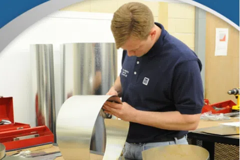 Apprentice working with sheet metal in workshop promoting apprenticeship credit for education.