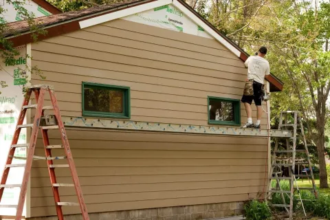 a person on a ladder painting a house